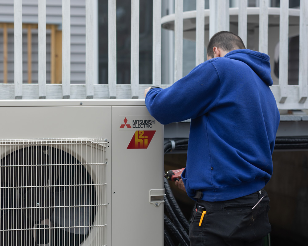 Technician working on a Mitsubishi Electric outdoor AC unit