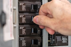 Person toggling a circuit breaker in an electrical panel