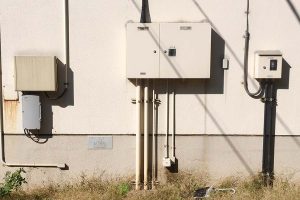 Utility meters and electrical equipment mounted on the exterior wall of a building.